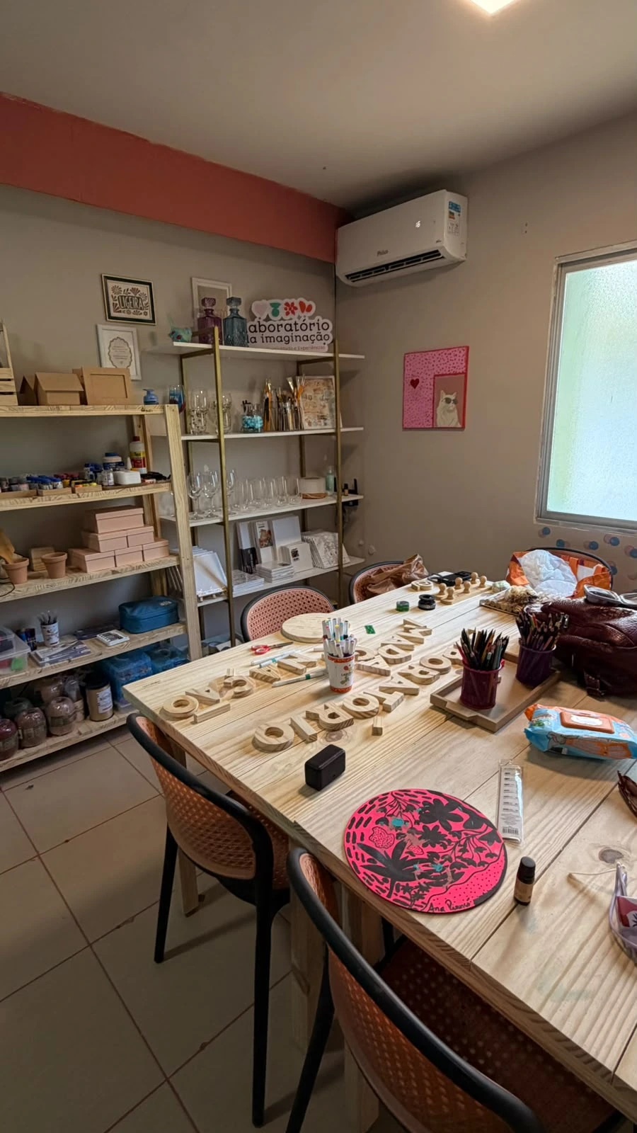 Mesa do ateliê preparada com tintas, pincéis e materiais antes de uma experiência
