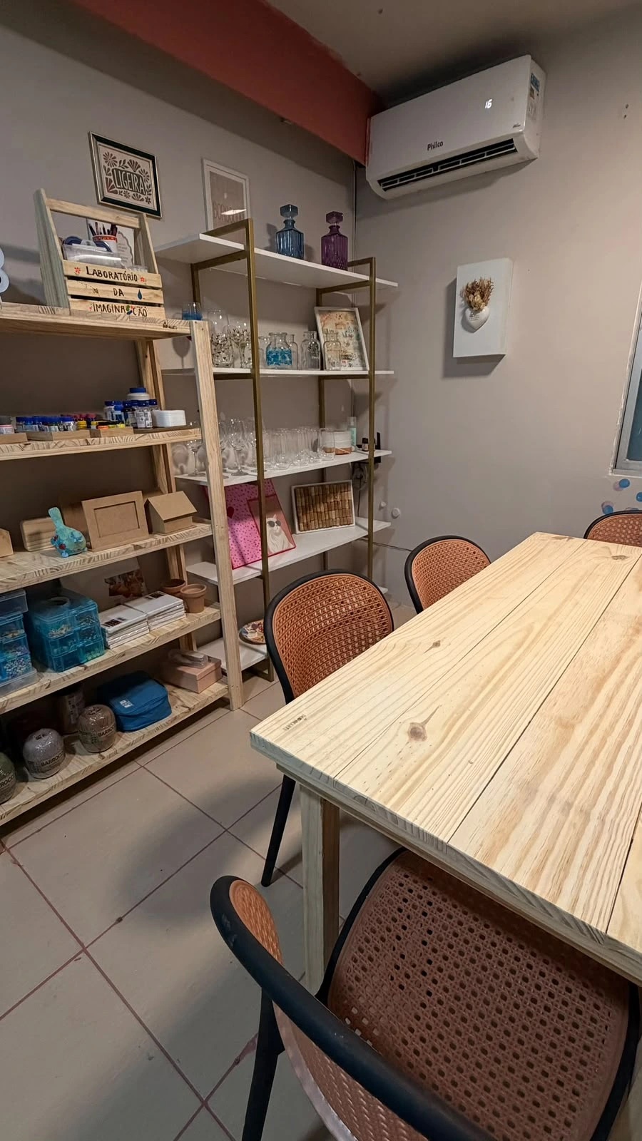 Espaço do Laboratório da Imaginação com mesa, cadeiras e prateleiras de materiais